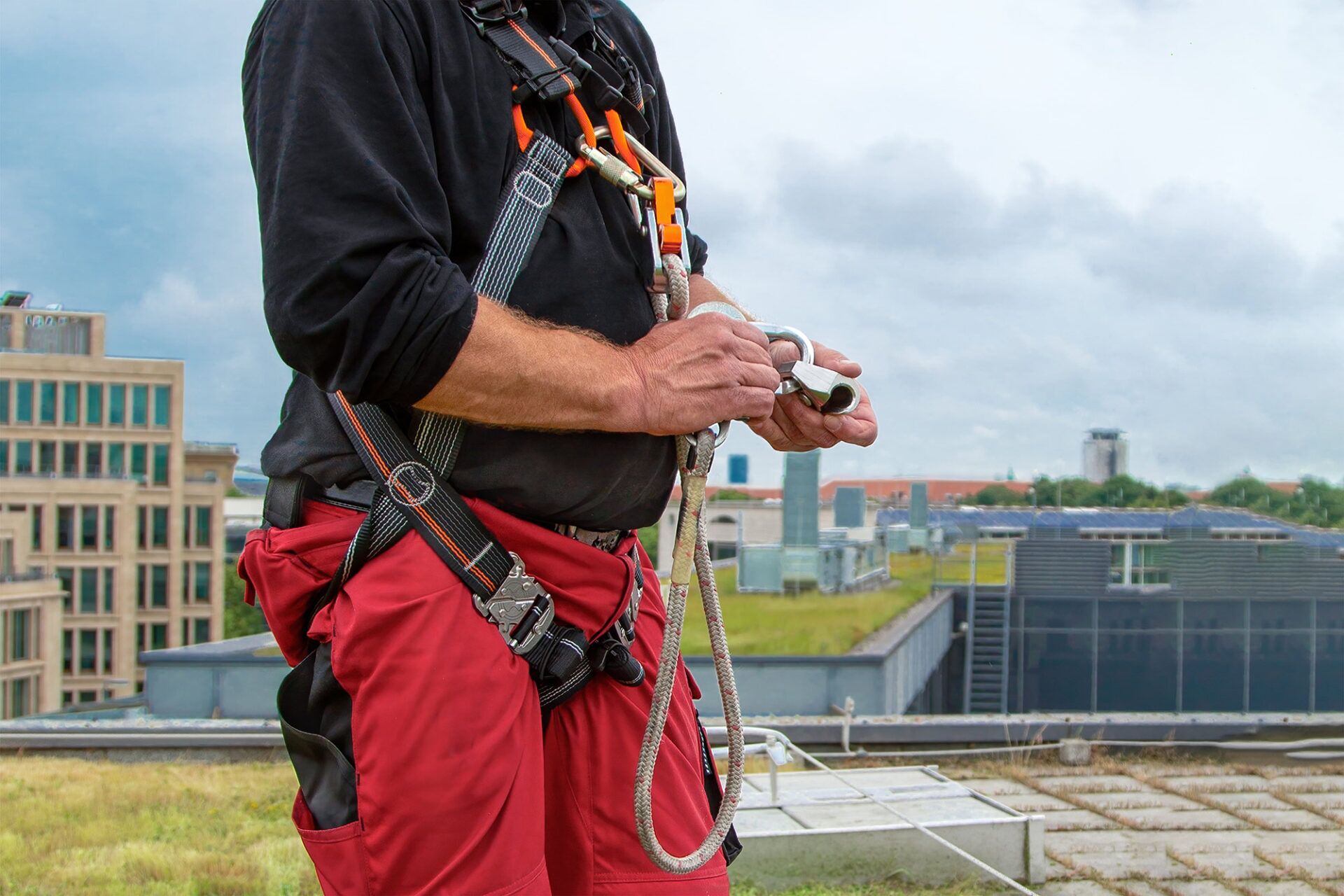 A worker demonstrating the restraint technique while working at heights, equipped with a harness and safety gear on a rooftop site.