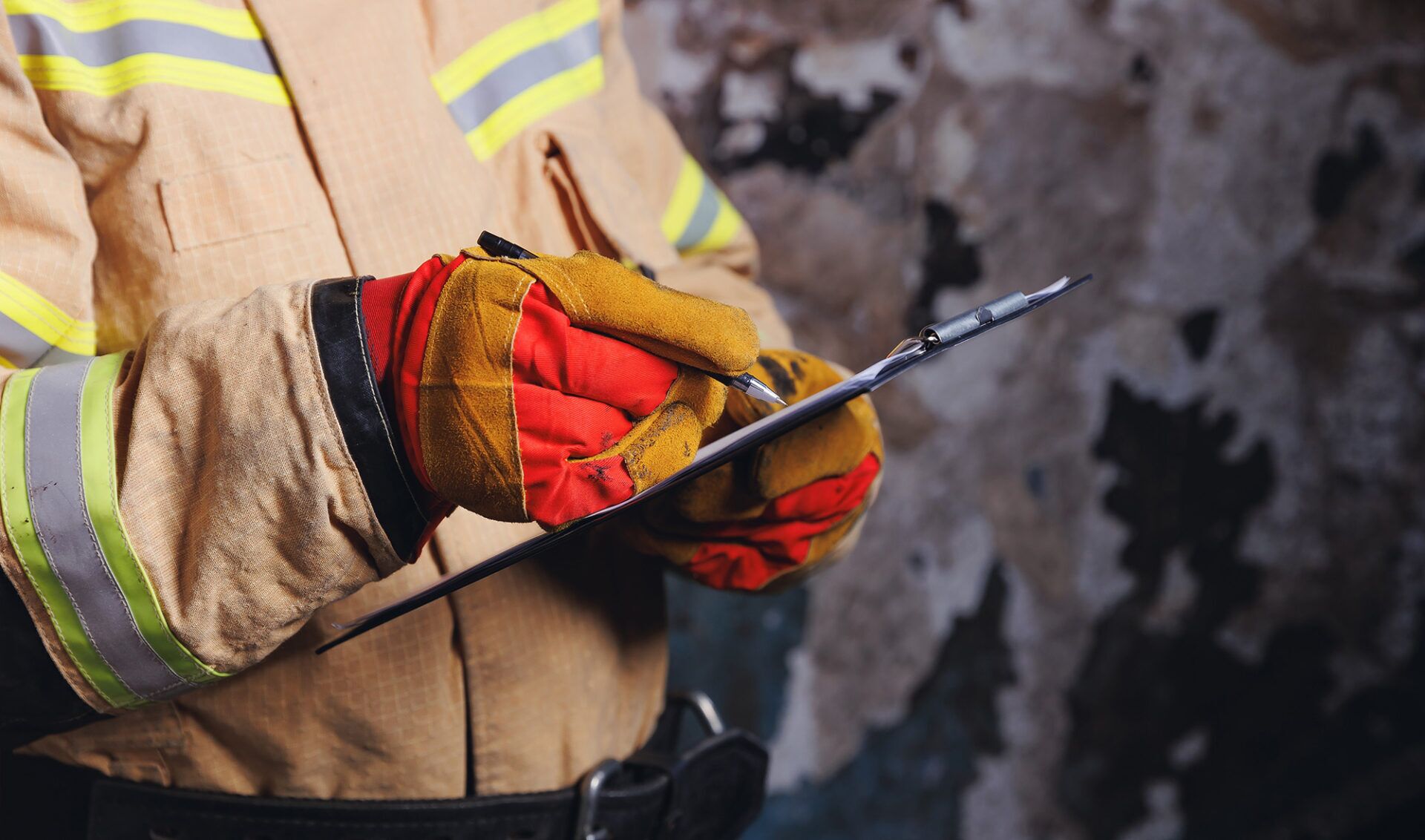 Individual in firefighter gear holding a clipboard and pen, symbolizing incident investigation training for entry-level personnel in Sydney.