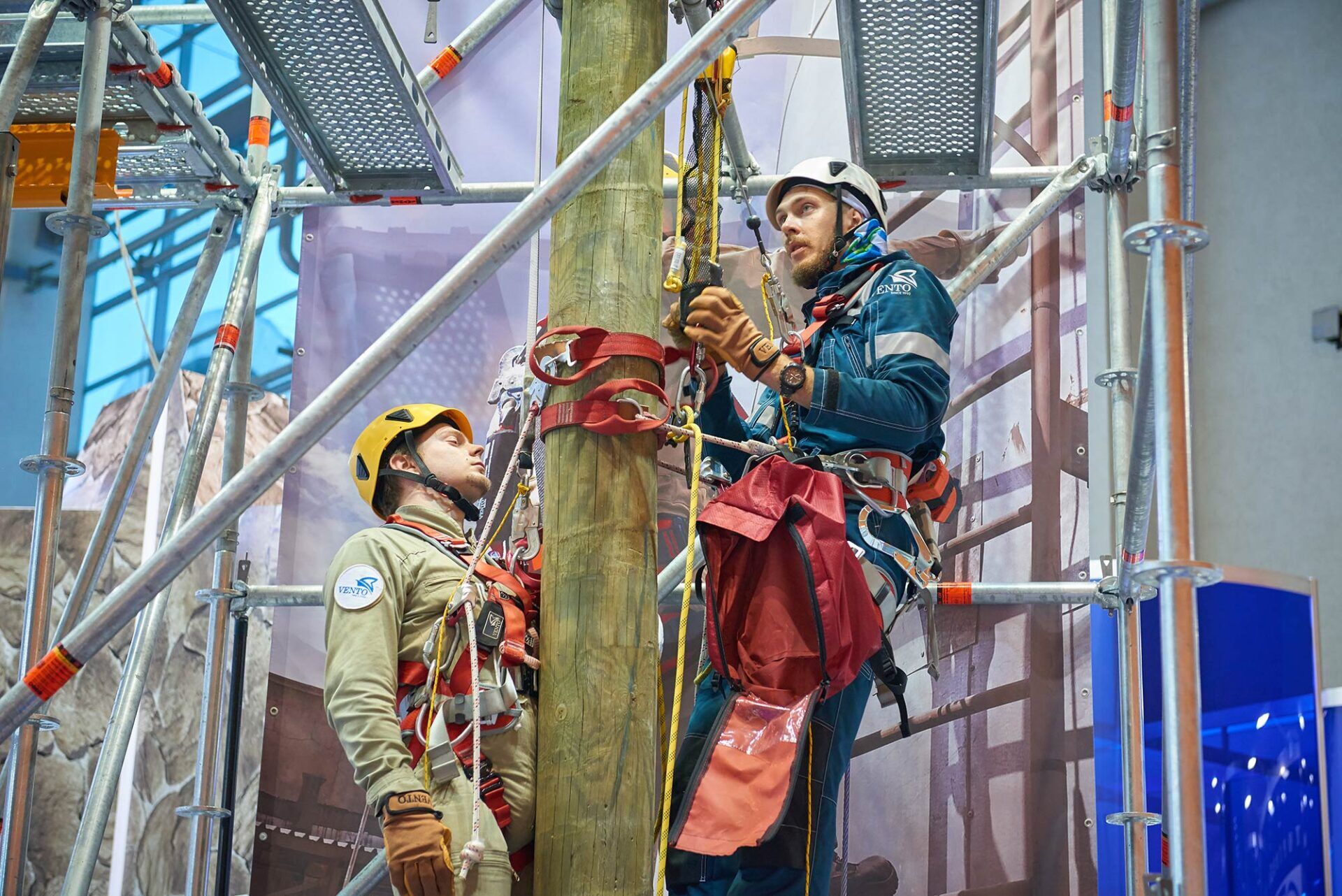 Two participants engaged in a weekend heights and confined space training course, demonstrating safety protocols while working on a wooden pole within a scaffolded environment.
